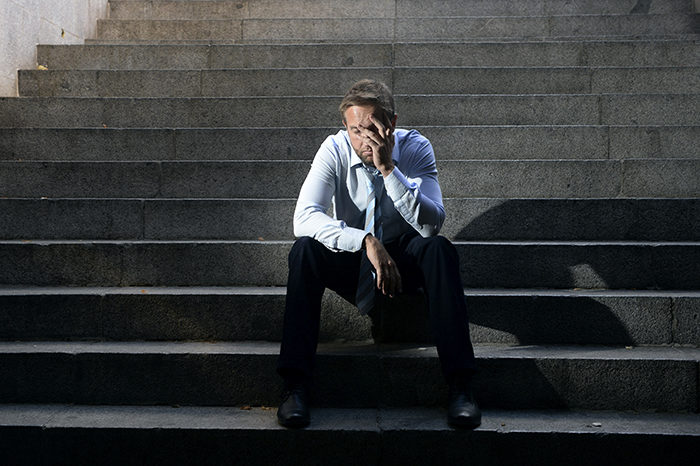 businessman crying lost in depression sitting on street concrete